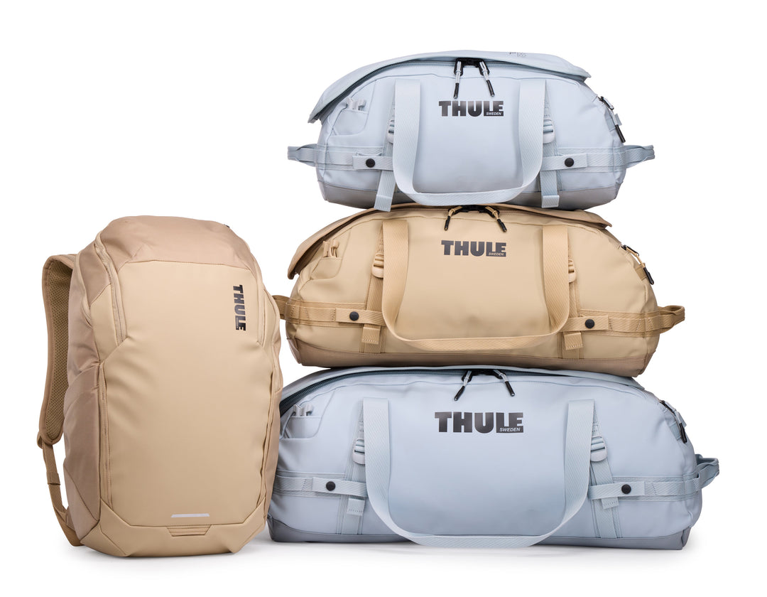 Stack of Thule bags including a backpack and duffels on a white background